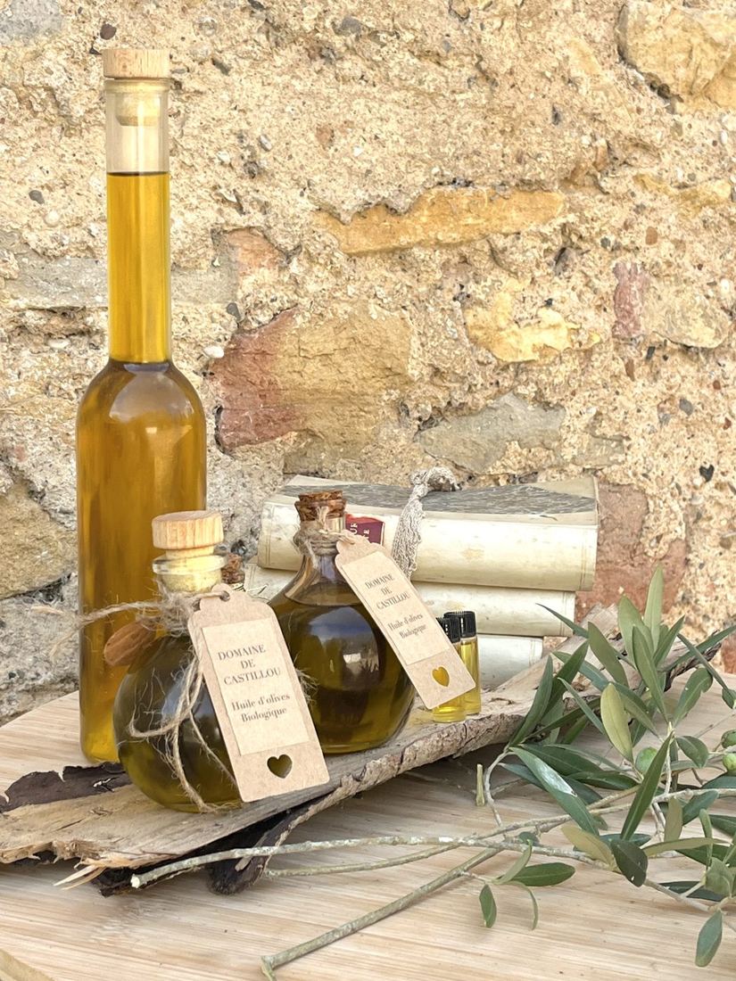 Les huiles d'olive biologiques du Domaine de Castillou, devant un mur en pierre