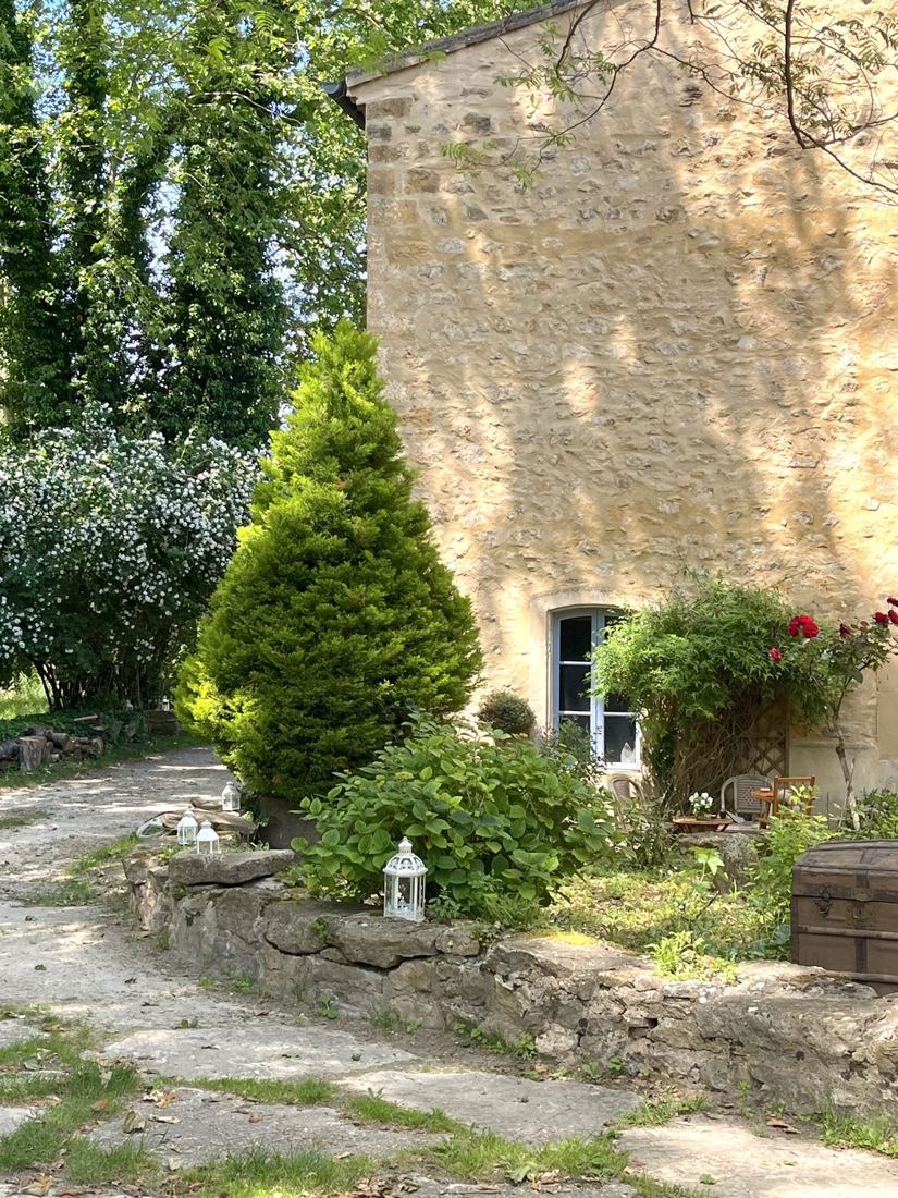 Le jardinet, ses lanternes et le seringat en fleurs au pied de la maison