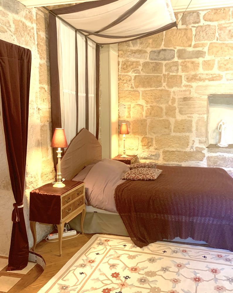La chambre de l'Évêque : lit à baldaquin et murs en pierre