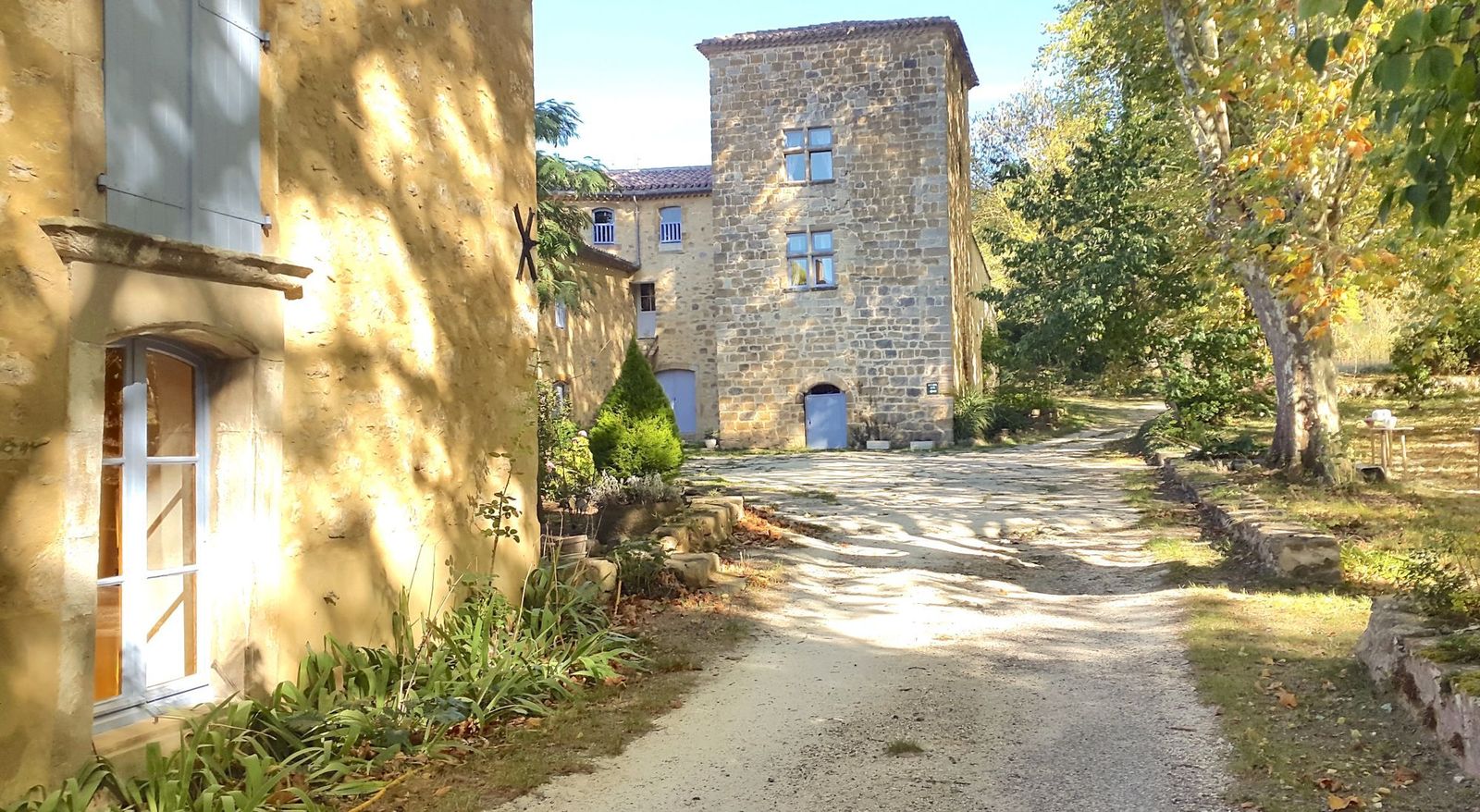 La cour de la Bâtisse et sa tour en pierre, à l'ombre des platanes