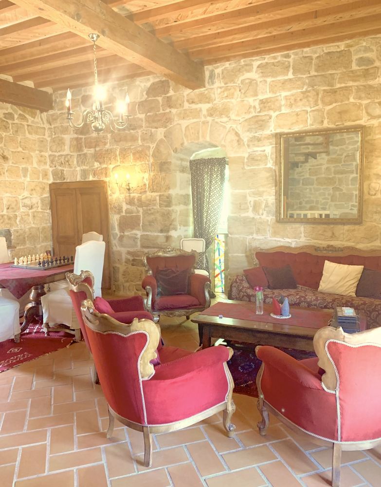 Le salon Rouge dans la tour : murs de pierre, poutres et fauteuils de velours