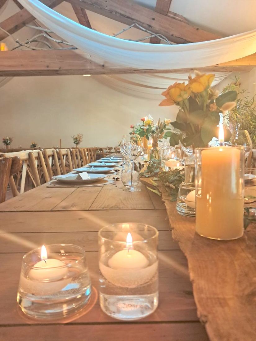 Tablée aux bougies dans la salle de réception, voilages et fleurs